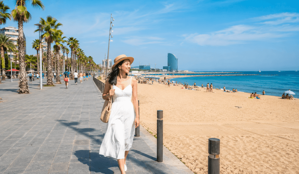 A woman walking along the beach in Barceloneta, Barcelona.